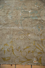 Distressed Sivas carpet detail: faded gold arabesques, muted blue, worn pile revealing foundation.