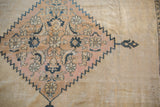 Distressed vintage Khorassan carpet with serrated diamond medallion, blush, and charcoal floral motifs.