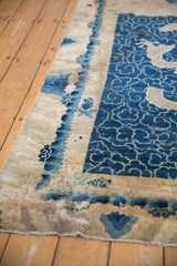 Distressed texture of the antique Peking rug's cobalt blue cloudband and aged ivory border.