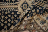 Folded distressed Malayer rug highlighting navy boteh patterns and textured beige border.