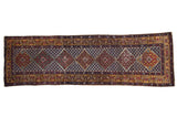 Vintage Caucasian runner with a column of geometric diamond medallions and a gold border over a dark blue lattice field.