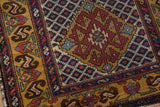 The intricate gold border and red diamond medallion corner of a vintage Caucasian runner.