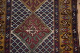 Close view of a vintage Caucasian rug's worn diamond medallion and indigo lattice design.