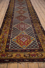 Angled perspective of a vintage Caucasian rug runner showing its repeating diamond medallion design.