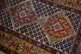 Mostly even wear to knot heads on a geometric medallion in wine red, gold, and deep indigo.