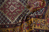 Interacting diamond and lattice motifs on a folded Caucasian runner in gold, wine red, and indigo.