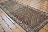 A long view of the distressed Hamadan runner, showing earthy diagonal stripes and a vine border.