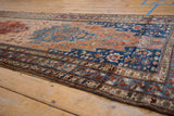 Angled view of a vintage Malayer runner showing its serrated rust medallion and blue floral field.
