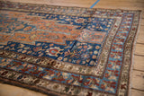 Angled view of a Malayer runner's corner showing intricate borders in rust, sky blue, and cobalt.