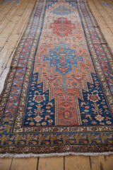 Perspective view down a vintage Malayer runner with serrated medallions in blue and dusty rose.