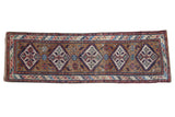 Antique Caucasian runner with diamond shaped medallions on an ochre field and a serpent-inspired rainbow border.