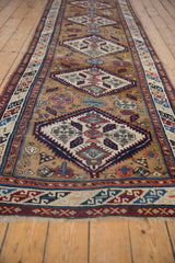 Angled view showing the geometric progression of diamond medallions on an antique Caucasian runner.