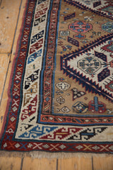 A detailed view of the Caucasian rug's geometric serpent border and low pile texture.