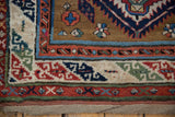 Corner view of an antique Caucasian rug's serpent motif border and original macrame end.