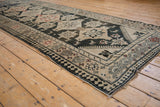 Angled shot of a vintage Karabagh runner, highlighting its detailed geometric border and low-pile texture.