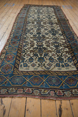 Distressed Kurdish Bijar runner close-up, ivory Herati field with intricate blue vine border.