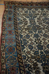 Vintage distressed Kurdish Bijar rug showing worn blue cartouche border and ivory floral patterns.