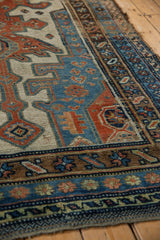 Geometric madder red, sky blue, and ivory patterns on distressed antique Kurdish runner.
