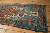 Distressed antique Kurdish runner, highlighting detailed indigo and rust borders with textured side.