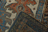 Distressed antique Kurdish rug detail: madder red, blue geometric pile, tattered edge, visible foundation.