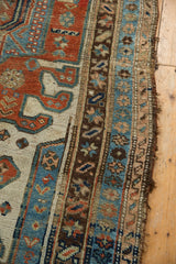 Aged edge of an antique Kurdish runner with geometric madder red, blue, and ivory borders.