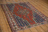 Angled view of a vintage Hamadan rug highlighting its stepped medallion in red and navy blue.