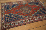 Angled perspective of a vintage Hamadan rug showing its geometric medallion, navy field and borders.
