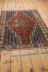 Angled view showing the geometric diamond medallion and stepped contours of a vintage Persian rug.