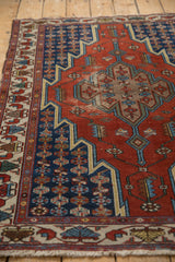 Angled view highlighting the lightning stepped contour on a vintage brick red and navy Hamadan rug.