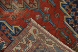 Corner detail of a vintage Hamadan rug, folded to show the hand-knotted texture and fringe.