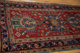 Vintage Fine Heriz rug detail: cherry red field, navy floral buds, hook and latch motifs, visible wear.