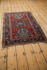 Heriz rug corner detail: cherry red field, navy border, and mostly intact polychrome selvage.