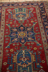 Heriz rug with cherry red field, navy blue finned floral motifs, and visible knot head wear.