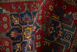 Close-up of vintage Heriz rug pile, showing cherry red field and detailed floral pinwheel motifs.