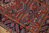 Heriz rug featuring sprawling geometric blossoms in brick red, navy, sky blue, and blush.