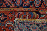 Vintage Heriz rug displaying geometric patterns in brick red, navy blue, and its hand-knotted foundation.
