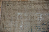 A distressed Malayer rug close-up showing worn pile, exposed foundation, and pale sky blue Herati motif.