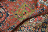 Vintage Heriz rug, folded to reveal geometric field, serrated leaves, and distinct border.