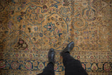 Vintage distressed Meshed rug with camel field, navy border, fuchsia motifs, and visible wear underfoot.