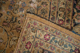 Folded corner of vintage distressed Meshed carpet, highlighting worn camel pile and pink border details.