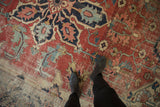 Worn brick red field of antique Serapi carpet with serrated leaves, navy blue, and exposed foundation.