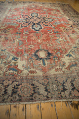 Detail of antique Serapi carpet showing worn brick red pile and navy serrated leaf motifs.