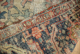 Antique Serapi hand-knotted carpet's worn pile, exposed foundation, and rich navy, brick red tones.