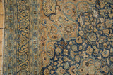 Detailed view of vintage Meshed rug with sand, navy, and light blue distressed floral arabesques.
