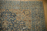 Distressed Persian Meshed rug corner with navy, sand, and light blue floral spandrel.