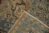 Distressed Meshed carpet's folded corner, highlighting faded sand and blue floral motifs with worn knot heads.