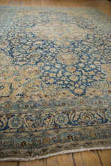 Distressed fringe and scrolling floral border on a vintage Meshed carpet with navy and sand.