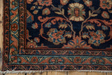 Vintage Persian Mehreban rug corner showing navy blue, dusty rose florals, intricate borders, and fringe.