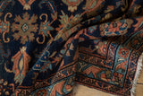Close-up of the vintage Mehreban rug with navy field, dusty rose floral border, and fringe.
