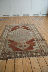 Distressed vintage Malayer rug corner with tattered fringe and geometric border in chestnut, slate blue.